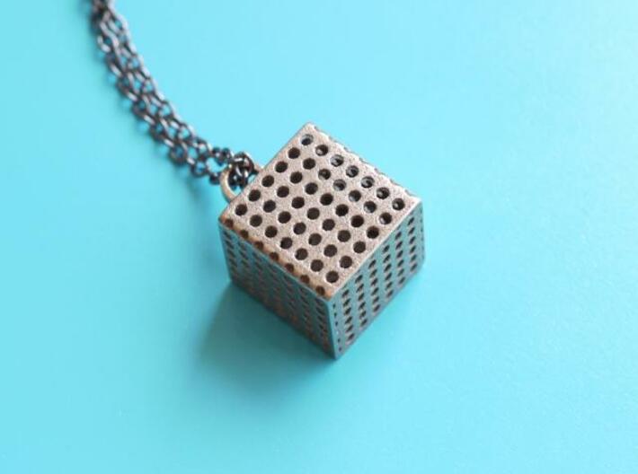 Perforated Cube Pendant  3d printed steel perforated cube on blue background