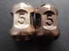 Five sided 'pepperpot' dice 3d printed Current version in stainless steel on left, previous version in polished bronze steel on right.