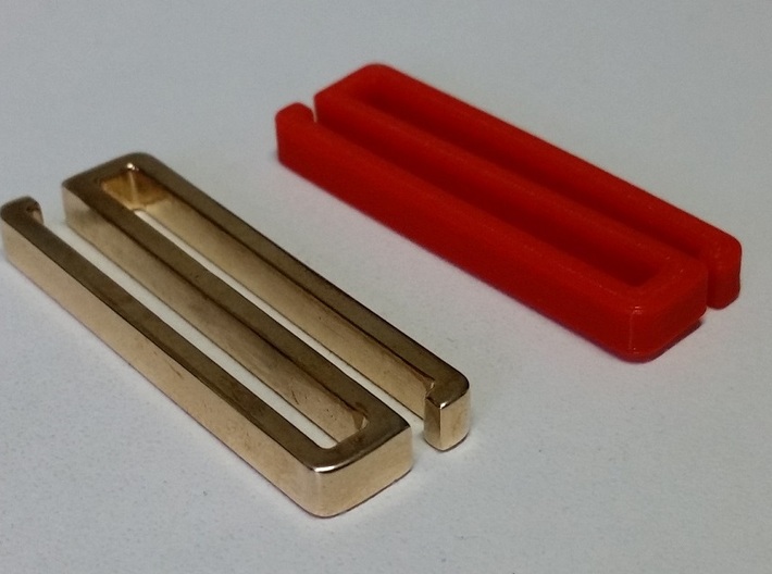 Belt clip, open. T41x4, shown: brass. 3d printed Final design of belt clip 41x4, in polished brass, accompanied by 1st design version in red PLA.