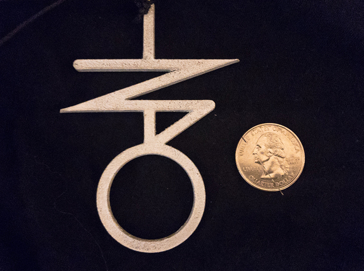 Bind Trump Sigil Pendant 3d printed Shown with quarter for scale. This is the metallic plastic option, but it has been coated with a metallic wax (after manufacture) for an aged lustre. 